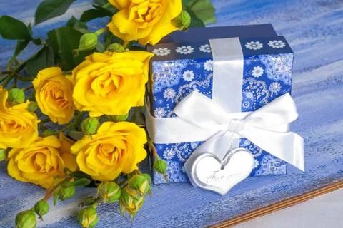 Blue present box and yellow roses on wooden tray Stock Photos