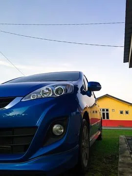 A blue Produa Alza car parked by the house. Stock Photos