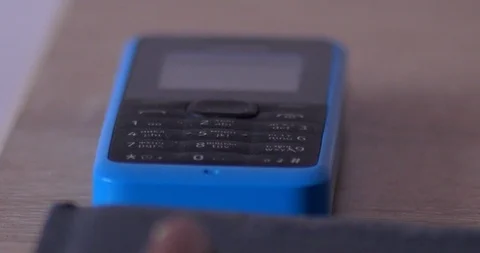 Blue push-button mobile phone starts to ring on table early in the morning Stockbeeldmateriaal 121909301