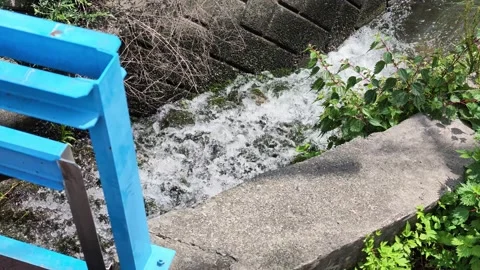 Blue railing frames rushing stream water Stock Footage 340238791