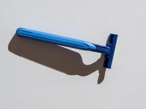 Blue razor on a gray background. Close-up, hard shadows Stock Photos