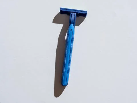 Blue razor on a gray background. Close-up, hard shadows Stock Photos