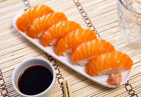 Blue rectangular ceramic plate of delicious salmon nigiri with soy souse on 库存照片