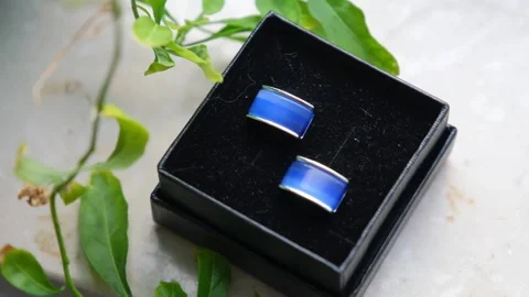 Blue rectangular cufflinks displayed in velvet box on textured surface Video stock 342026012