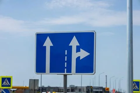 Blue rectangular road sign featuring white straight and right turn arrows p.. Stock Photos