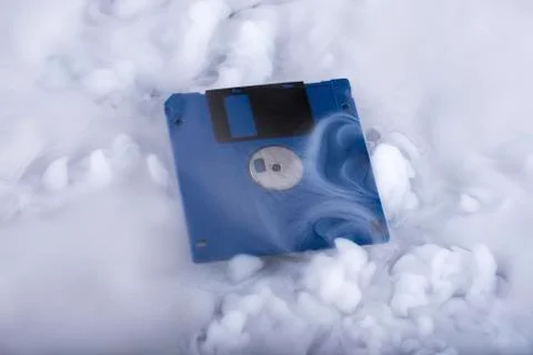 Blue retro floppy disk in clouds. Information cloud. Conceptual Stock Photos