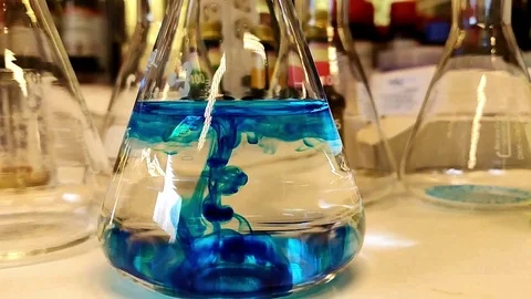 Blue reverse chemical reaction drop in water in a chemistry conical flask  Stock Footage 105960174
