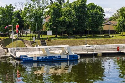Blue River Boat Docked by a Tree-Lined Park Pier in Summer Leisure Scene, A.. 스톡 사진
