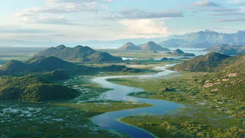 Blue river flowing through green valley toward distant mountains Stock Footage 133376449