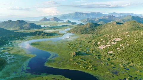 Blue river flowing through green valley toward distant mountains Stock Footage 133399896