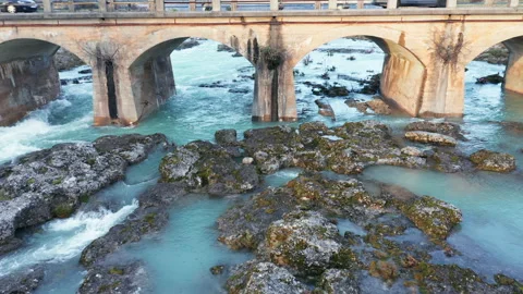 Blue river flowing under an arch bridge through beautiful rocky landscape Stock Footage 211618663