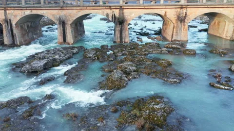 Blue river flowing under an arch bridge through beautiful rocky landscape Stock Footage 211730321