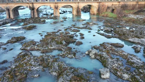 Blue river flowing under an arch bridge through beautiful rocky landscape Stock Footage 211745409