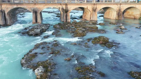 Blue river flowing under an arch bridge through beautiful rocky landscape Stock Footage 211778412