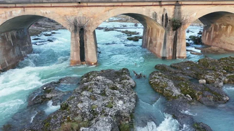 Blue river flowing under an arch bridge through beautiful rocky landscape Stock Footage 211788146