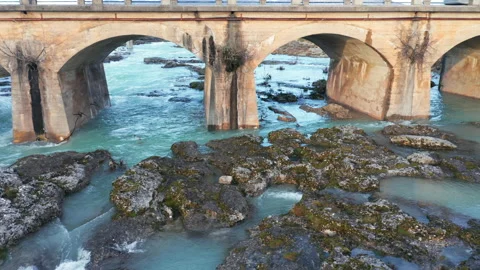 Blue river flowing under an arch bridge through beautiful rocky landscape Stock Footage 211793737