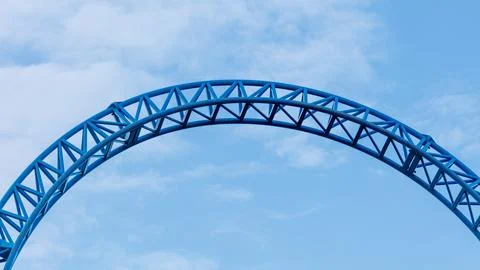 Blue roller coaster loop against a clear sky Foto stock