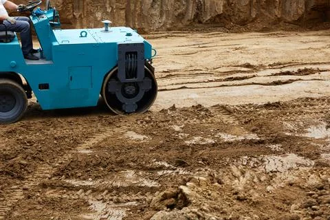 Blue roller compacts the ground on freshly dug soil at a construction site .. Stock-Fotos