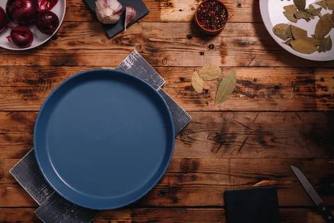 Blue round empty plate on dark brown wooden background, top view Stock Photos