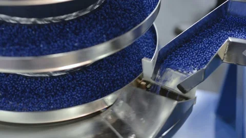 The blue round granules move up the vibrating screw conveyor. Stock Footage 89441329