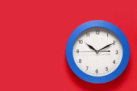 Blue round wall clock on red background, time management and deadline concept Stock Photos