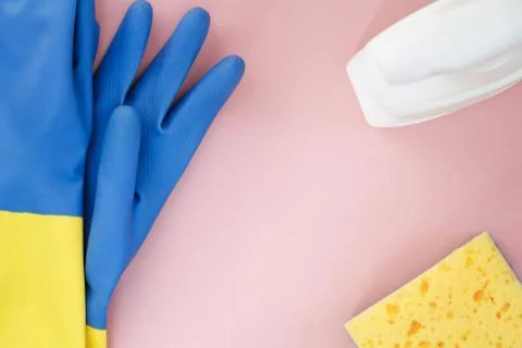 Blue rubber gloves, white atomizer and yellow sponge for washing on a pink Stock Photos