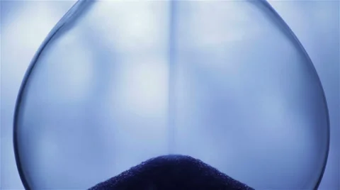 Blue Sand falling in hourglass on light background. Extreme close-up Stock Footage 67413859