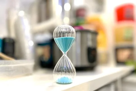 Blue sand timer on a white surface. Stock Photos