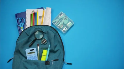 Blue school backpack with supplies on a blue background. Stop motion Stock Footage 309475206