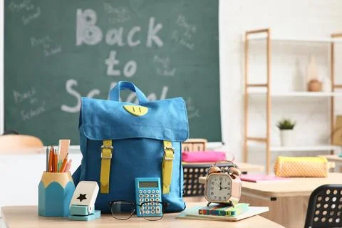 Blue School backpack with supplies on a classroom desk, Back to School with c Stock Photos