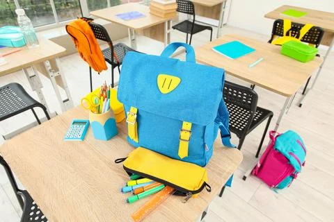 Blue school backpack with yellow straps and pencil case on a wooden desk in a Stock Photos
