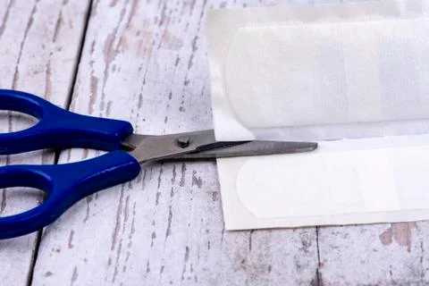Blue scissors cuts a plaster open Stock Photos