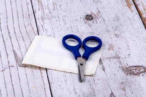 Blue scissors with plaster on white rustic wood Stock Photos