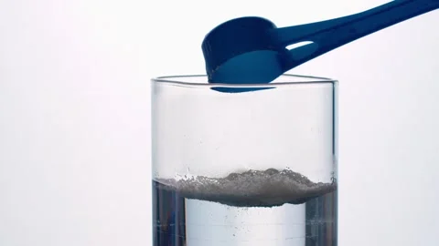 Blue Scoop Adding Powder to Water Glass with Bubbling Foam Reaction 動画素材 336602314