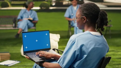 Blue screen chroma key on laptop held by black medical student Stock Footage 340961444