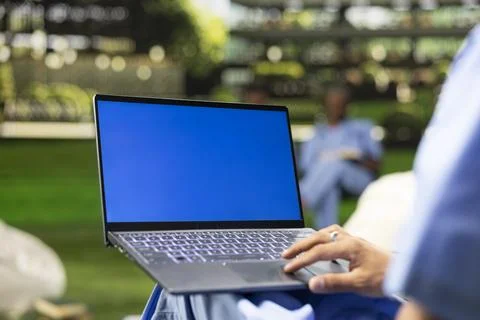 Blue screen laptop mockup held by student using touchpad with one hand Stock Photos