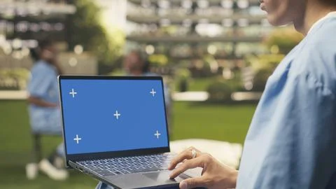 Blue screen laptop mockup held by student using touchpad with one hand Stock Photos