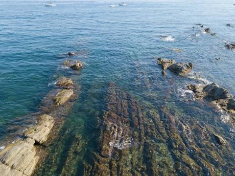 Blue sea with rocks underneath Stock Photos