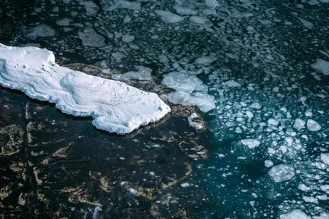 Blue sea surface with thin ice texture and snow on the rocks Stock Photos
