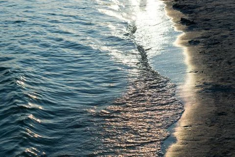 Blue sea waves with rays of light and sandy beach filtered Stock Photos