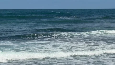 Blue sea waves roll toward shore in steady motion, forming rhythmic water Stock Footage 330297522