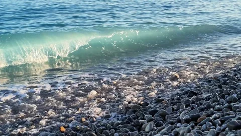Blue sea waves washing onto pebble beach at sunset 스톡 동영상 336922792