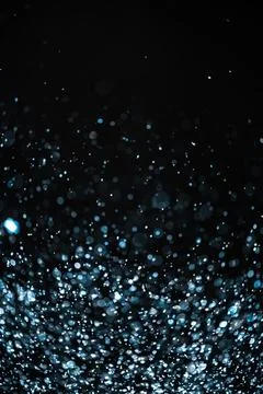 Blue sequins fall on a black background Stock Photos