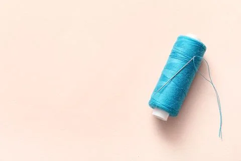 Blue sewing thread with needle on beige background Stock Photos