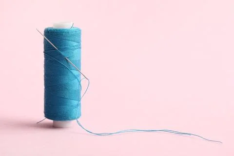 Blue sewing thread with needle on pink background Stock Photos