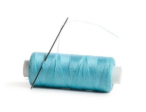 Blue sewing thread spool with needle isolated on white background, closeup Stock Photos