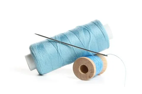 Blue sewing thread spools with needle isolated on white background, closeup Stock Photos