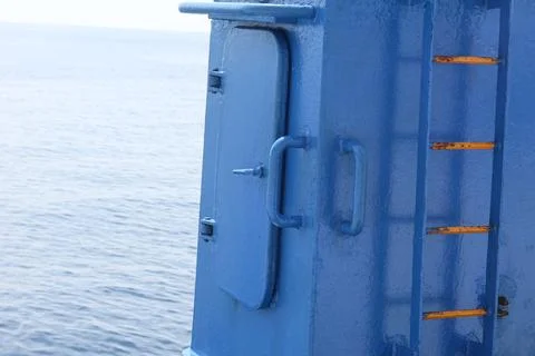 Blue Ship Access Door and Ladder Above Calm Ocean 写真素材