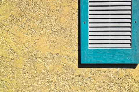 Blue shutter on yellow exterior wall Stock Photos