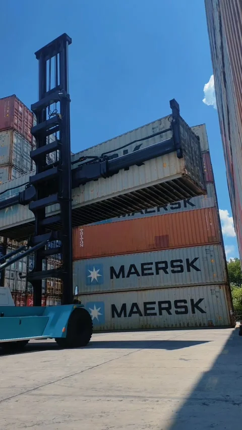 Blue side loader managing cargo containers in a bustling shipping yard Stock Footage 312021889